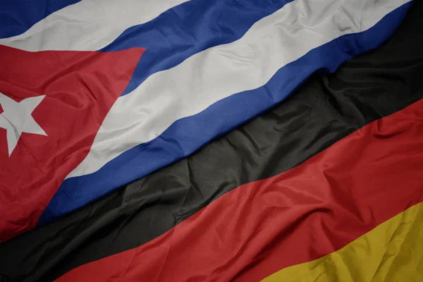 Agitant drapeau coloré de l'Allemagne et drapeau national de cuba . — Photo