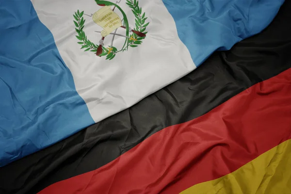 Ondeando colorida bandera de Alemania y bandera nacional de Guatemala . — Foto de Stock