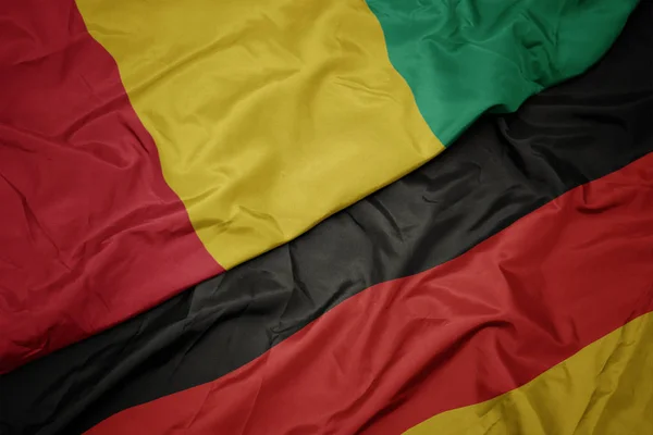 Ondeando bandera colorida de Alemania y bandera nacional de Guinea . —  Fotos de Stock