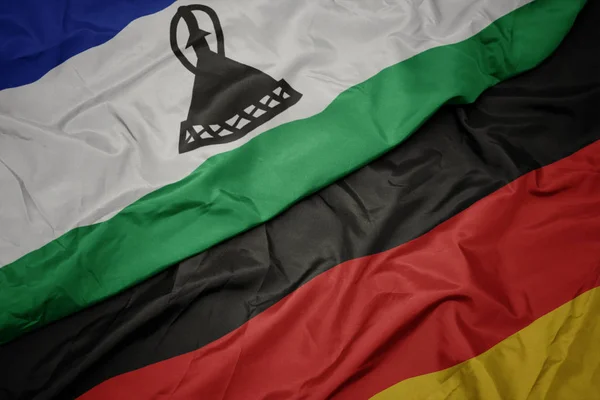 Acenando bandeira colorida da alemanha e bandeira nacional do lesotho . — Fotografia de Stock