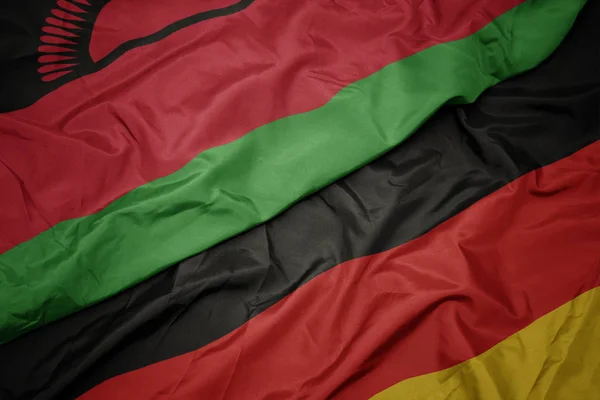 Waving colorful flag of germany and national flag of malawi. — Stock Photo, Image