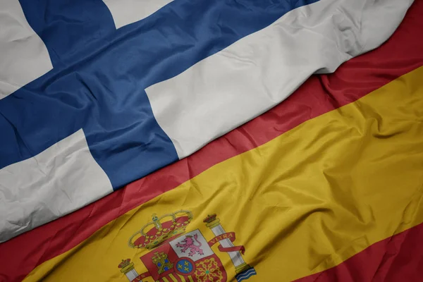 Waving colorful flag of spain and national flag of finland. — Stock Photo, Image