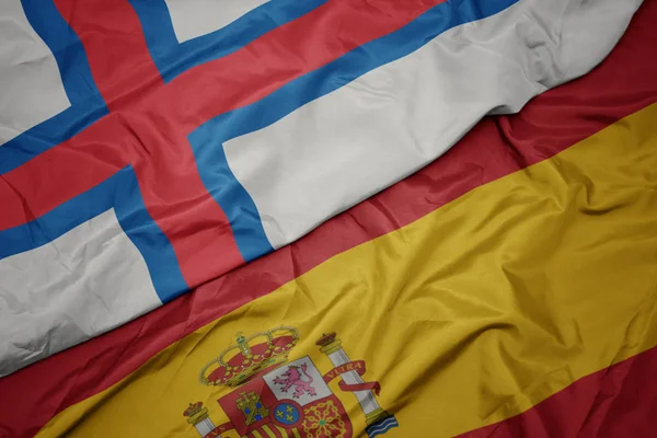 Agitant drapeau coloré de l'Espagne et drapeau national des îles Féroé . — Photo