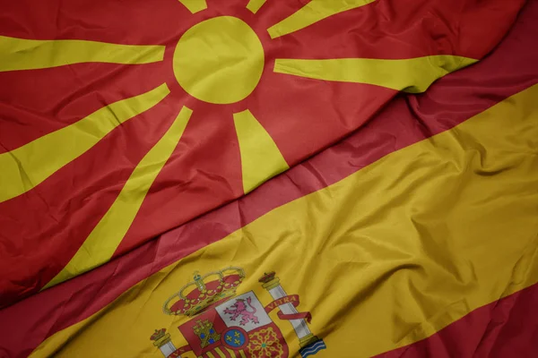 Acenando bandeira colorida da espanha e bandeira nacional da macedônia . — Fotografia de Stock