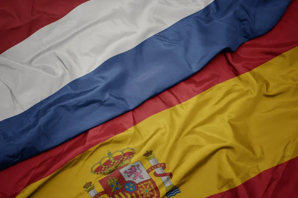 Vinka färgglada flagga av Spanien och nationella flaggan i Nederländerna. — Stockfoto