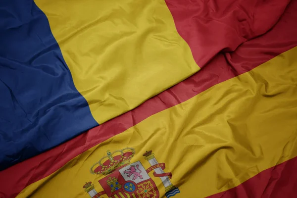 Waving colorful flag of spain and national flag of romania. — Stock Photo, Image