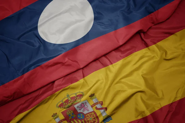 Размахивая красочным флагом Испании и национальным флагом Лаоса . — стоковое фото
