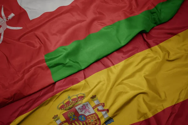 Waving colorful flag of spain and national flag of oman. — Stock Photo, Image