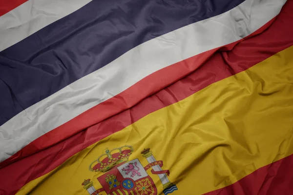 Mávající barevná vlajka Španělska a národní vlajky Thajska. — Stock fotografie