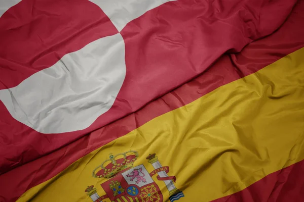 Sventolando bandiera colorata della Spagna e bandiera nazionale della Groenlandia . — Foto Stock
