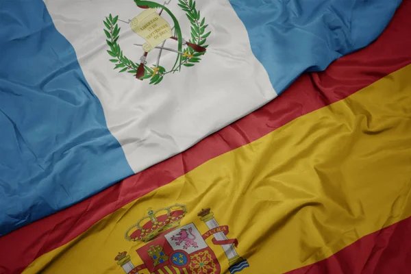 Ondeando colorida bandera de España y bandera nacional de guatemala . —  Fotos de Stock