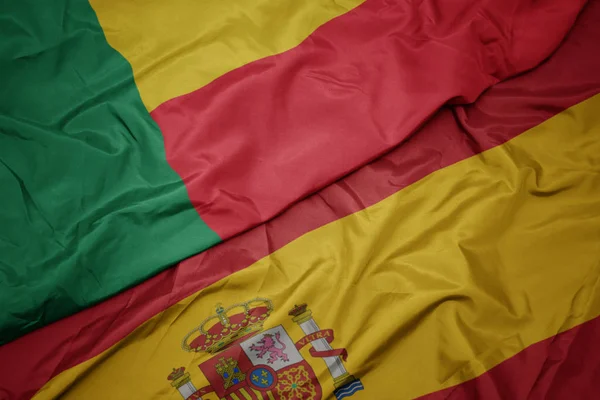 Waving colorful flag of spain and national flag of benin. — Stock Photo, Image