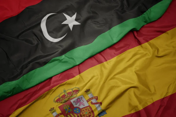 Agitant drapeau coloré de l'Espagne et drapeau national de libya . — Photo