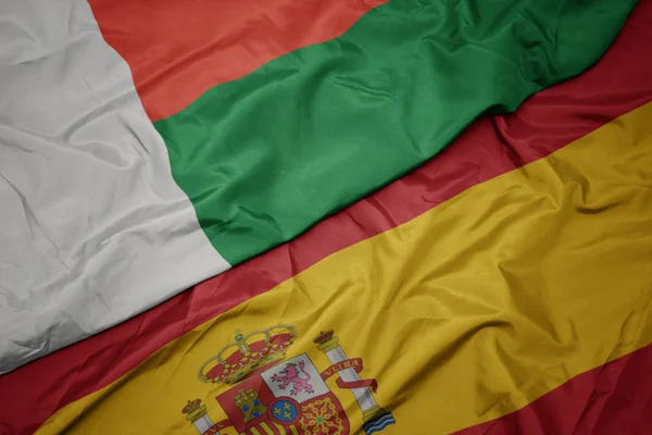 Waving colorful flag of spain and national flag of madagascar. — Stock Photo, Image