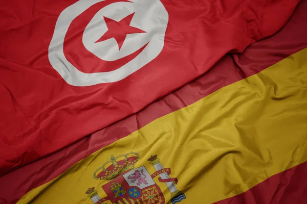 Agitant drapeau coloré de l'Espagne et drapeau national de la Tunisie . — Photo