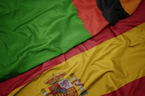Integetett színes spanyol zászló és Zambia nemzeti zászlaja. — Stock Fotó