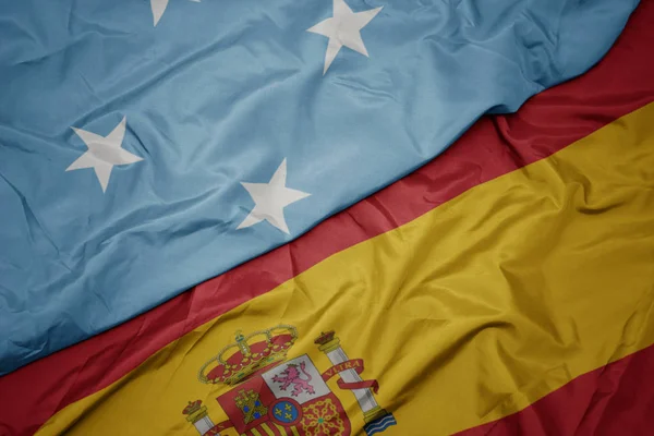 Agitant le drapeau coloré de l'Espagne et le drapeau national des États fédérés de Micronésie . — Photo