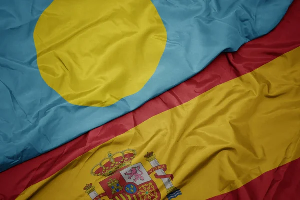 挥舞着五颜六色的西班牙国旗和帕劳国旗. — 图库照片
