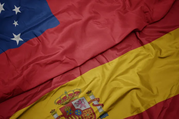 Zwaaiende kleurrijke vlag van Spanje en de nationale vlag van Samoa. — Stockfoto