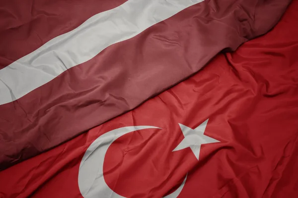 Mávající barevnou vlajku Turecka a národní vlajky Lotyšska. — Stock fotografie