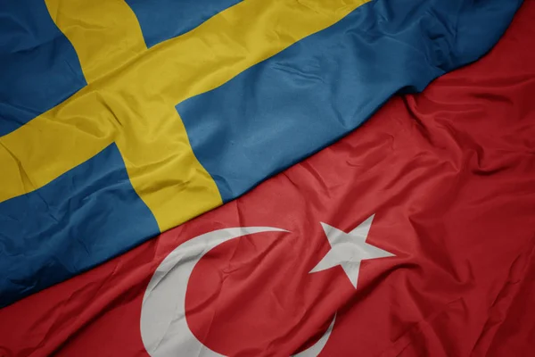 Türkiye'nin renkli bayrağını ve İsveç'in ulusal bayrağını sallıyor. — Stok fotoğraf