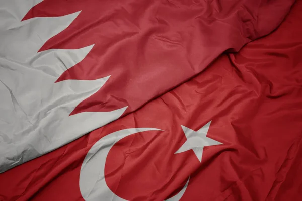 waving colorful flag of turkey and national flag of bahrain.