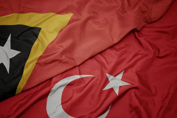 Ondeando colorida bandera de pavo y bandera nacional de Timor Oriental . — Foto de Stock