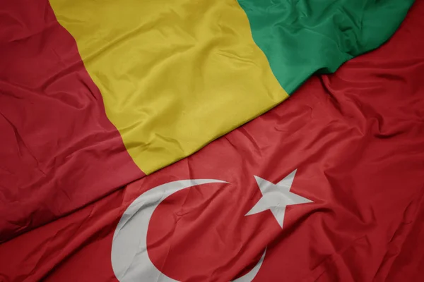 Türkiye ve gine ulusal bayrağı renkli bayrak sallayarak. — Stok fotoğraf