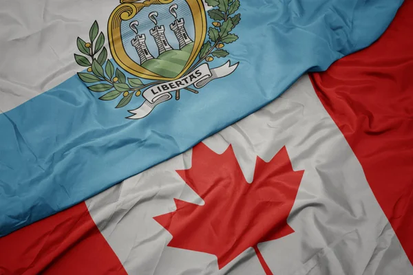 Integetett a kanadai zászló és San Marino nemzeti zászlaja. — Stock Fotó