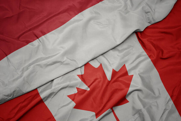 waving colorful flag of canada and national flag of indonesia.