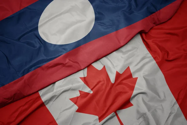 Acenando bandeira colorida do Canadá e bandeira nacional do Laos . — Fotografia de Stock