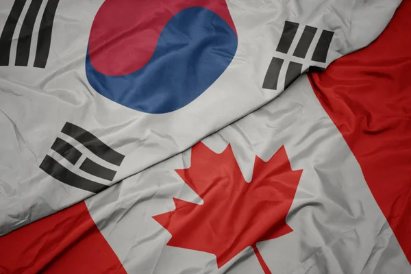 Acenando bandeira colorida do Canadá e bandeira nacional da Coréia do Sul . — Fotografia de Stock
