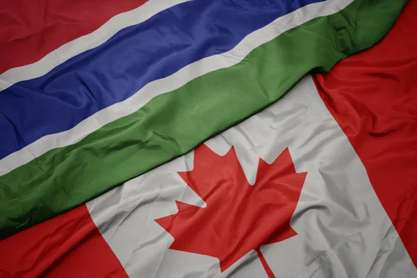 Zwaaiende kleurrijke vlag van Canada en de nationale vlag van Gambia. — Stockfoto