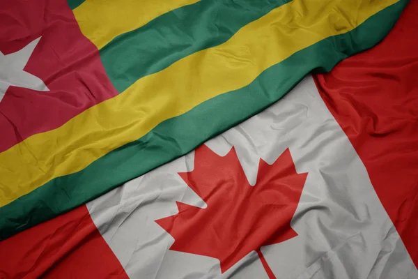 Schwenken bunte Fahne von Kanada und Nationalflagge von Togo. — Stockfoto