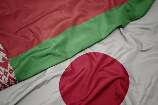 waving colorful flag of japan and national flag of belarus.