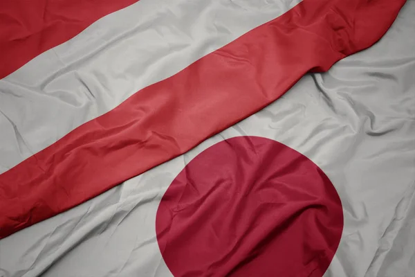 waving colorful flag of japan and national flag of austria.