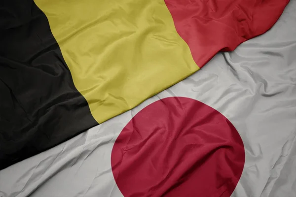 Zwaaiende kleurrijke vlag van Japan en de nationale vlag van België. — Stockfoto