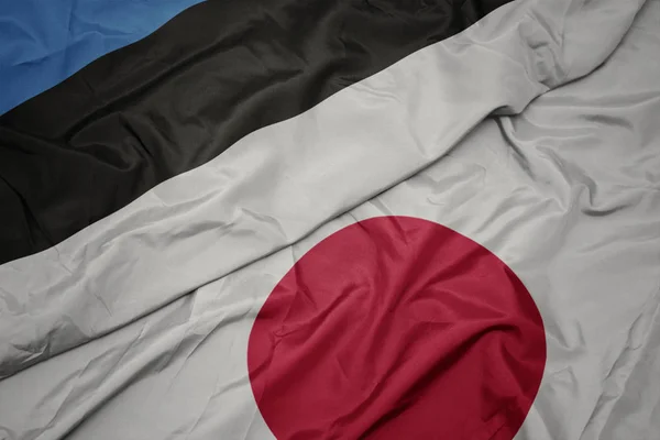 waving colorful flag of japan and national flag of estonia.