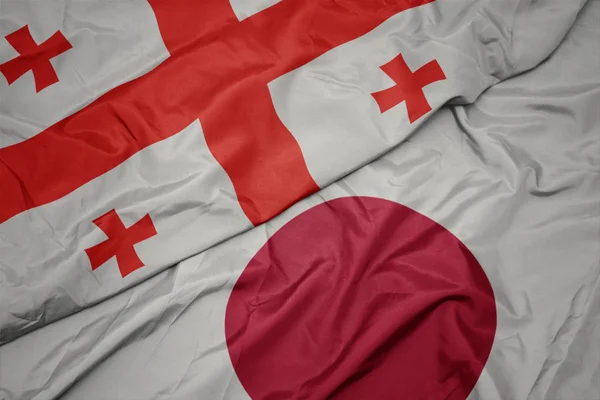 Mávající barevná vlajka Japonska a národní vlajky Gruzie. — Stock fotografie