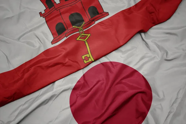 waving colorful flag of japan and national flag of gibraltar.