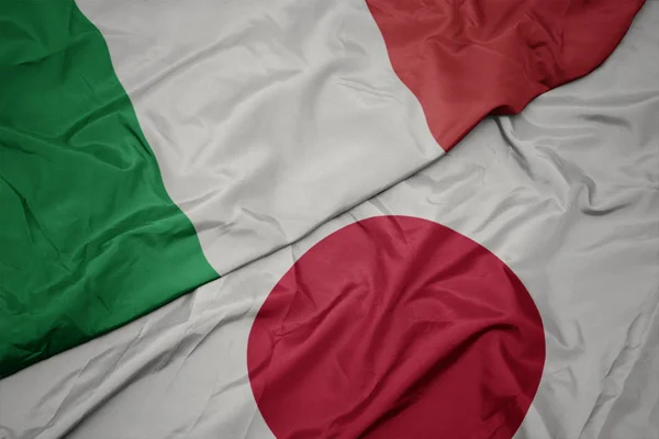 waving colorful flag of japan and national flag of italy.