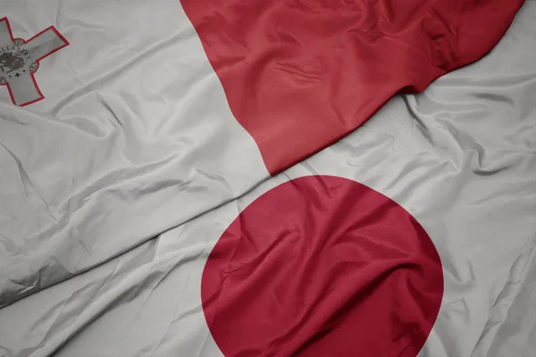 waving colorful flag of japan and national flag of malta.