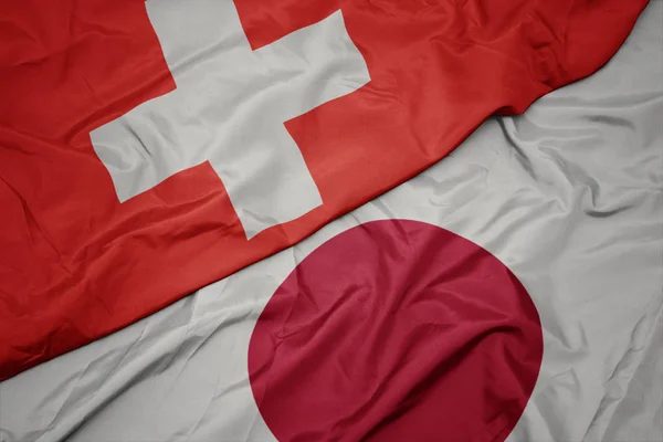Falujące kolorowe flagi Japonii i Narodowej flagi Szwajcarii. — Zdjęcie stockowe