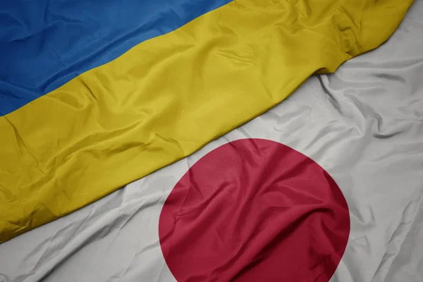 Acenando bandeira colorida do japão e bandeira nacional da Ucrânia . — Fotografia de Stock