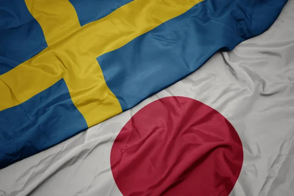 Размахивая красочным флагом Японии и национальным флагом Швеции . — стоковое фото