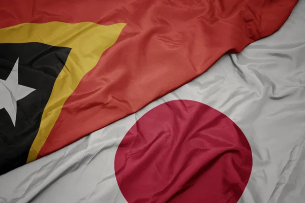 waving colorful flag of japan and national flag of east timor.