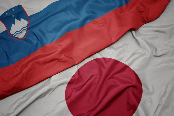 waving colorful flag of japan and national flag of slovenia.