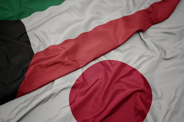waving colorful flag of japan and national flag of kuwait.