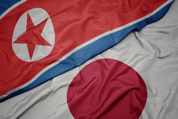 Falujące kolorowe flagi Japonii i flagi narodowej Korei Północnej. — Zdjęcie stockowe
