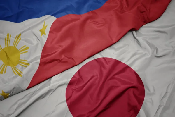 waving colorful flag of japan and national flag of philippines.